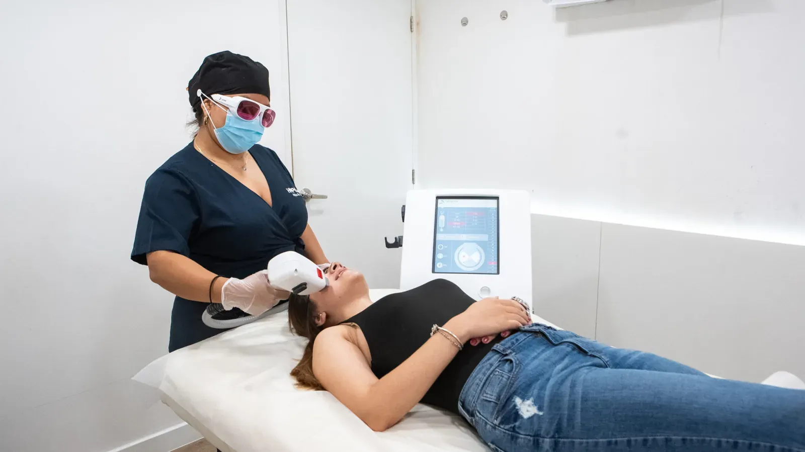 Especialista de HAPPYláser con gafas de protección tratando el rostro de una clienta